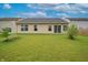 Large, level backyard with green grass, a tan home, and a sliding glass door at 2390 Lakecrest Dr, Columbus, IN 47201