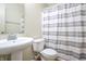 Clean bathroom featuring a pedestal sink, toilet, and a shower with a gray and white striped curtain at 2390 Lakecrest Dr, Columbus, IN 47201
