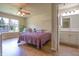 Comfortable bedroom featuring hardwood floors, a ceiling fan, a large window, and an en suite bathroom at 2390 Lakecrest Dr, Columbus, IN 47201