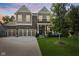 Charming two-story home at dusk featuring a three-car garage, brick accents, covered porch, and lush lawn at 4285 Nottinghill Dr, Avon, IN 46123