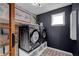 Modern laundry room with black washer and dryer, floral wallpaper, and brick-patterned flooring at 4285 Nottinghill Dr, Avon, IN 46123