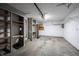 The image captures a garage interior with open shelving, white walls, a concrete floor, and an overhead door with an opener at 562 Monte Vista Dr, Greenwood, IN 46143