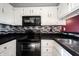 Well-lit kitchen featuring sleek black appliances, white cabinetry, and stylish tiled backsplash at 562 Monte Vista Dr, Greenwood, IN 46143