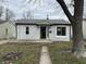 A quaint one-story home featuring horizontal siding, gray roof, a small porch and walkway leading to the entrance at 5810 Greenfield Ave, Indianapolis, IN 46219