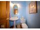 Powder room with pedestal sink, gold mirror, modern lighting, and light blue painted walls at 6013 Yellow Birch Ct, Avon, IN 46123