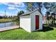 Exterior view of storage shed on property featuring a red door near a picturesque pond for added convenience and charm at 6026 Sally Ann Cir, Indianapolis, IN 46237