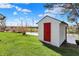 Exterior view of storage shed featuring a red door set on a tranquil pond for functional storage and aesthetic appeal at 6026 Sally Ann Cir, Indianapolis, IN 46237