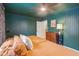 Bedroom features green trim, light wood floors, a ceiling fan, and an orange bedspread at 6481 Michigan Rd, Indianapolis, IN 46268