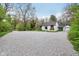 Extended gravel driveway leading to a charming white house, showcasing ample parking and a tranquil setting at 6481 Michigan Rd, Indianapolis, IN 46268