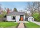 Charming home features a bright orange door, updated landscaping, and a brick chimney at 6481 Michigan Rd, Indianapolis, IN 46268
