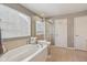 Bright bathroom with tub and glass shower, window with blinds and neutral tile flooring at 6681 Keepsake Dr, Whitestown, IN 46075