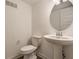 Modern powder room with a pedestal sink, oval mirror, and a toilet with a chrome handle at 6953 Equality Blvd, Carmel, IN 46033