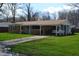 Ranch home with a carport, featuring a brick facade, green lawn, and mature trees at 838 Highland Dr, Whiteland, IN 46184