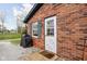 Charming brick home featuring a side entrance with a storm door and gray shutters at 89 E Walnut St, Fountaintown, IN 46130