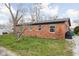 Rear exterior of a brick home featuring a grassy lawn and mature trees at 89 E Walnut St, Fountaintown, IN 46130