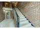 Carpeted staircase with brick wall, iron railing, and a landing featuring a wreath-adorned door at 102 Knoll Ct # D, Noblesville, IN 46062