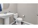 A well-lit powder room features a pedestal sink, modern faucet, and classic toilet at 1075 Barberry Dr, Greenwood, IN 46143