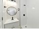 A bathroom with a shower, white sink and a black trimmed circular mirror at 1145 N Belleview Pl, Indianapolis, IN 46222