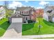 Beautiful two-story home with a lush green lawn, brick facade, and red shutters under a partly cloudy sky at 11741 Langham Crescent Ct, Fishers, IN 46037