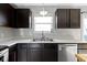 Close-up of a kitchen sink and dishwasher area with dark wood cabinetry and white countertops at 11741 Langham Crescent Ct, Fishers, IN 46037