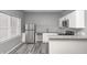 Modern kitchen featuring stainless steel appliances, white cabinets, gray backsplash, and wood floors at 11975 Civic Cir, Mooresville, IN 46158
