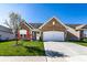 Charming brick home featuring a well-manicured lawn, blossoming tree, and attached two-car garage, all under a clear blue sky at 1371 Blackthorne N Trl, Plainfield, IN 46168