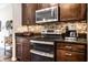 Gourmet kitchen with modern appliances, dark cabinetry, and granite countertops with stylish backsplash at 1371 Blackthorne N Trl, Plainfield, IN 46168