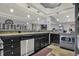 Basement wet bar featuring stainless steel dishwasher, dark cabinetry, and granite countertop at 14019 Colville Cir, Carmel, IN 46033