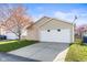 Attached two-car garage with a white door and concrete driveway, accented by a tree on a sunny day at 14317 Banister Dr, Noblesville, IN 46060