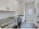 Functional laundry room with modern washer and dryer, white cabinets, and an exterior door at 1472 Windpump Way, Carmel, IN 46280
