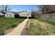 Backyard view towards detached garage with door entry, bordered by greenery and a chain-link fence at 2050 Winton Ave, Indianapolis, IN 46224
