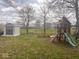 Wide backyard showcases a play-set, shed, grass, mulch, and mature trees at 2517 Horton Dr, Anderson, IN 46011