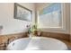 Bright bathroom featuring a soaking tub with tile surround and natural light from a large window at 267 Westbrook Ct, Columbus, IN 47201
