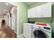 Bright laundry room features modern washer and dryer with white cabinets against a green wall at 267 Westbrook Ct, Columbus, IN 47201