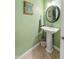 Green powder room featuring a pedestal sink, round mirror, and decorative accents with tile flooring at 267 Westbrook Ct, Columbus, IN 47201
