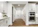 Bright hallway with white trim, hardwood floors, and access to kitchen appliances at 2779 Ruffian Dr, Westfield, IN 46074