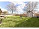 Expansive backyard featuring a shed, lush green grass, surrounded by mature trees and a wooden fence at 3607 Windsor Way, Anderson, IN 46011
