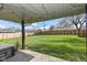 Expansive backyard featuring a lush green lawn, wooden fence, and covered patio with overhead string lights at 3607 Windsor Way, Anderson, IN 46011