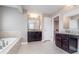 Double vanity with dark cabinets, granite countertop, and large tub at 3728 Dunellen Cir, Carmel, IN 46074