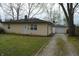 View of home's exterior and a detached garage, showcasing the home's driveway and small yard at 4431 Bertrand Rd, Indianapolis, IN 46222
