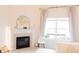 Bright interior view of fireplace, adjacent to a large window and a stylish white chair and coffee table at 5301 Tanglewood Ln, Whitestown, IN 46075