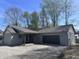 View of the home's exterior featuring an attached garage, gravel driveway and covered porch at 609 W Pearl St, Trafalgar, IN 46181