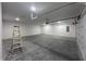 A spacious garage with tall ceilings, concrete floors and bright lighting with a white door at 609 W Pearl St, Trafalgar, IN 46181