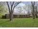 Beautiful backyard with a well-manicured lawn and mature trees surrounding a classic brick home at 7026 Spring Mill Rd, Indianapolis, IN 46260