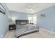 Blue bedroom with a large bed, ceiling fan, and bright windows providing natural light at 7026 Spring Mill Rd, Indianapolis, IN 46260
