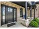 Inviting front porch with a dark door, beautiful stone pillars, and stylish hanging plants at 725 Meadowbrook Ln, Franklin, IN 46131