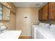 Bright laundry area features wood floors, upper cabinets, sink, and modern white washer and dryer at 7260 Marla Dr, Indianapolis, IN 46256