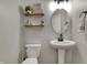 Stylish half bathroom with a pedestal sink, decorative shelves, and patterned wallpaper at 8734 Blue Marlin Dr, Indianapolis, IN 46239