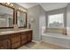 Bathroom featuring a double sink vanity, a soaking tub, and a window at 8734 Blue Marlin Dr, Indianapolis, IN 46239