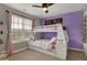 Cozy bedroom featuring a bunk bed, purple accent wall, and natural light from the window at 8734 Blue Marlin Dr, Indianapolis, IN 46239